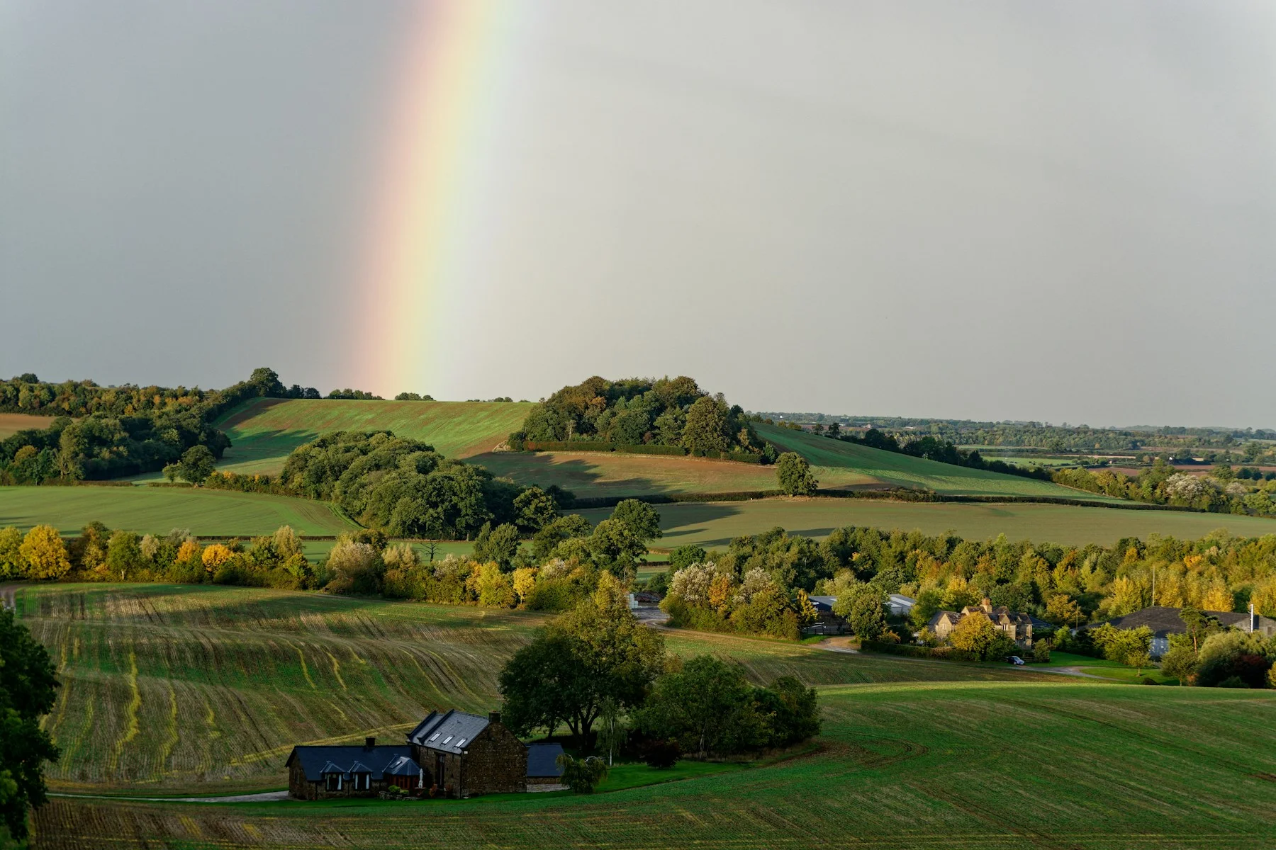 Rainbow over green fields and hedgerows in the Cotswolds